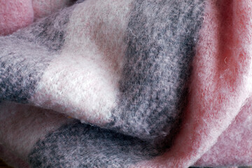 Woolen scarf in pastel colors, pink, gray and white. Cozy texture close up. Concept of comfort. Blanket scarf.