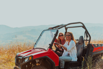 Two young happy excited women enjoying beautiful sunny day while driving a off road buggy car on mountain nature © .shock