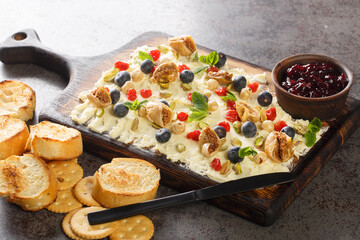 Flat lay of a butter board topped dried cherries and figs, pistachios, hazelnuts, fresh blueberries and mint served with toasts and crackers close-up on the table. Horizontal