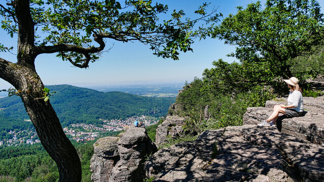 Frau sitzt auf den Battertfelsen und genie&szlig;t die Wanderpause zum Ausblick auf Baden-Baden
