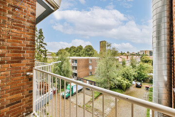 a balcony with brick walls and white railings, looking out onto the back yard from an apartment in...