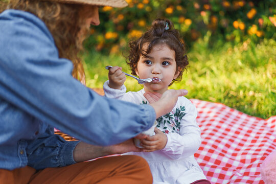 Close-up of a young girl enjoying yogurt with her mother in nature