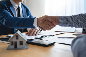 Young businessman and financial representative shaking hands after a budget deal for business expansion and investment in a village construction project real estate financial concept.