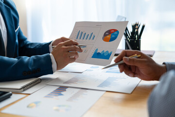 Young Asian businessman analyzing and discussing and brainstorming chart data. financial report graph in the office financial advisor and accounting concept.