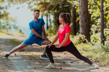 Couple enjoying in a healthy lifestyle warming up and stretching before jogging - obrazy, fototapety, plakaty