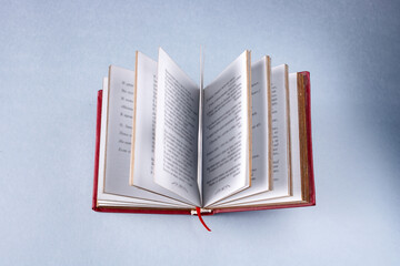 an open book in a red cover on a blue background, selective focus