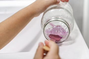 Chemical experiment on growing crystals. Child hands take out grown crystal from a jar. Steps by...