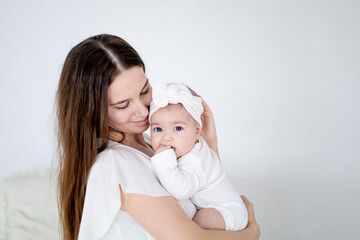 mom is holding a small newborn baby girl at home on a green background. Maternal love and care, space for text