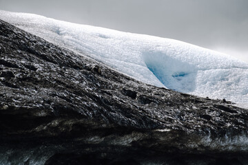 View of a blue iceberg broken off from the glacier tongue of Fjallsjökull in the glacier lagoon Fjallsárlón in Iceland on a cloudy day. 