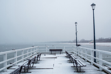 Snowy pier with white railings and cold baltic sea in winter