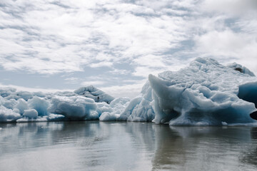 View of a blue iceberg broken off from the glacier tongue of Fjallsjökull in the glacier lagoon Fjallsárlón in Iceland on a cloudy day. With a view of Öræfajökull in the background.
