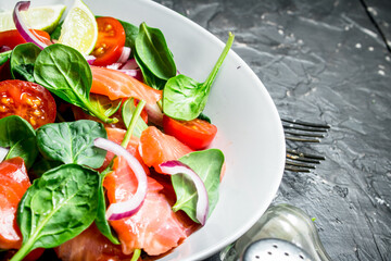 Fish salad. Salad with slices of salmon, tomatoes and spinach with lime juice.