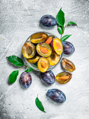 Pieces of fresh plum in a bowl with leaves.