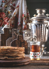 Fototapeta na wymiar Pancakes for Maslenitsa. A stack of Russian thin pancakes. Samovar and tea on the table.Traditional Russian festive food. Country style.