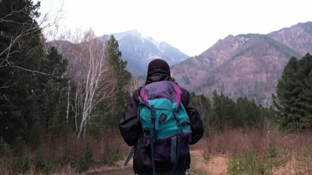 concept of travel. a tourist with a backpack walks along a forest trail into the mountains. beautiful mountain landscape. an exciting hike in the mountains. enjoying nature. slow motion.