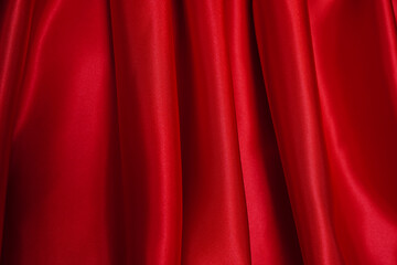 Bright red curtains are beautifully wavy, close-up.