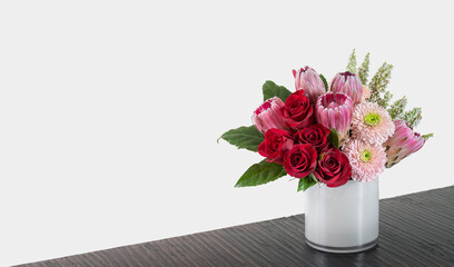 Flower arrangement pink and red colors, Romance, Valentine’s Day, Professional Florist created flower arrangement in a round white glass vase on table. Floral shop concept. Luxury, upscale, elegant.