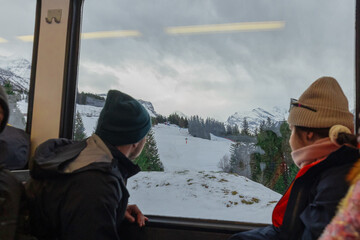 Unknown people looking out from the window of a panoramic car of Jungfrau narrow gauge railway on a winter day.