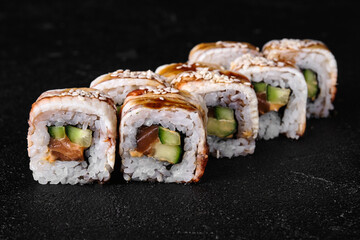 Eel sushi roll with cream cheese, cucumber and red caviar of fish black concrete background
