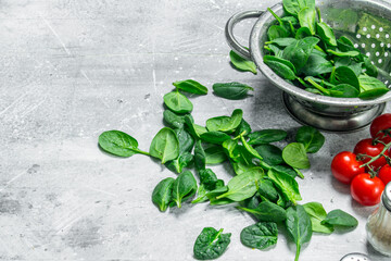 Spinach leaves in a saucepan and tomatoes on a branch.