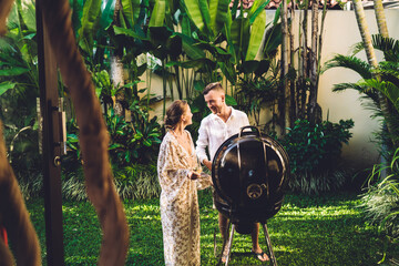 Caucaisan husband preparing barbeque meal at holidays vacations with carefree wife, young male and...