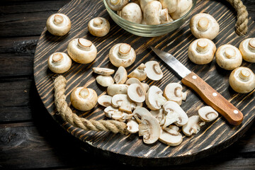 Mushrooms in a bowl and pieces of mushrooms on a tray with a knife.