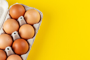 Chicken eggs in a tray on a yellow background. Home products. Easter holiday concept.