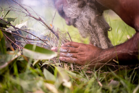 Aboriginal man making a fire with sticks and leaves