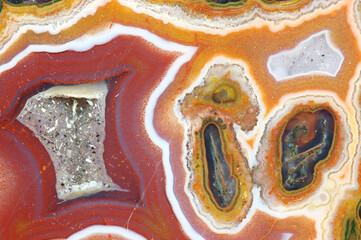 A cross section of the agate stone with quartz geode. Multicolored silica bands colored with metal oxides are visible. Macro photography of the surface of the cut. Origin: Atlas mountains, Morocco. - obrazy, fototapety, plakaty