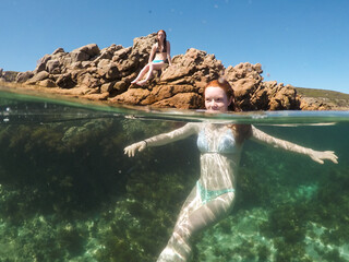 Two teenage girls playing in an ocean rock pool