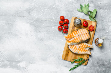 Grilled salmon steaks with tomatoes and a sprig of rosemary.