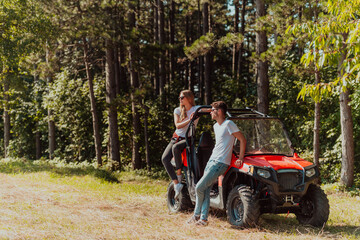 Young happy excited couple enjoying beautiful sunny day while driving a off road buggy car on mountain nature