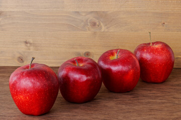 Red apple fruits. Four raw ripe perfect apples on wooden table.