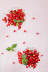 Fresh red currants in crystal glasses on a pink background