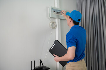 An Asian young Technician service man wearing blue uniform checking electrical appliances in home