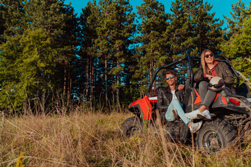 Fototapeta na wymiar Young happy excited couple enjoying beautiful sunny day while driving a off road buggy car on mountain nature