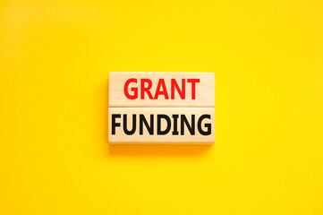 Grant funding symbol. Concept words Grant funding on wooden blocks. Beautiful yellow table yellow background. Business and grant funding concept. Copy space.