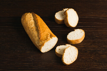 French baguette with an appetizing crust cut into pieces on a wooden background close-up