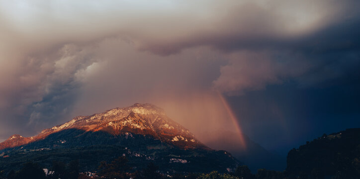 Storm front over the Alps mountains in Switzerland. Rain clouds and rainbow.