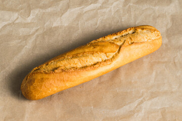Delicious French baguette close-up, on baking paper. Concept of development of craft bakeries