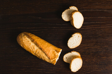French baguette with an appetizing crust cut into pieces on a wooden background close-up