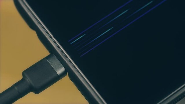 Close up charging indication on screen of mobile phone with connected type c cable. Modern technology concept