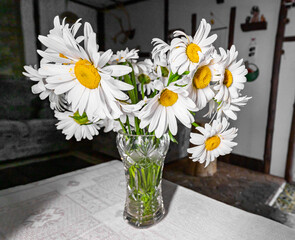 Chamomile flowers, camomile floral bunch, field wild plants in vase on table with white cloth in country style