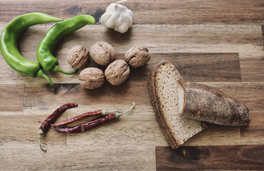 Shelled walnuts, red hot pepper, green sweet pepper a head of garlic, bread made from natural wheat on a wooden table. Healthy eating food low carb ketogenic diet plan.