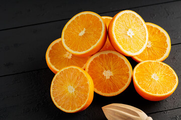 Bright halves of oranges on a wooden table. Halves of juicy oranges on black boards
