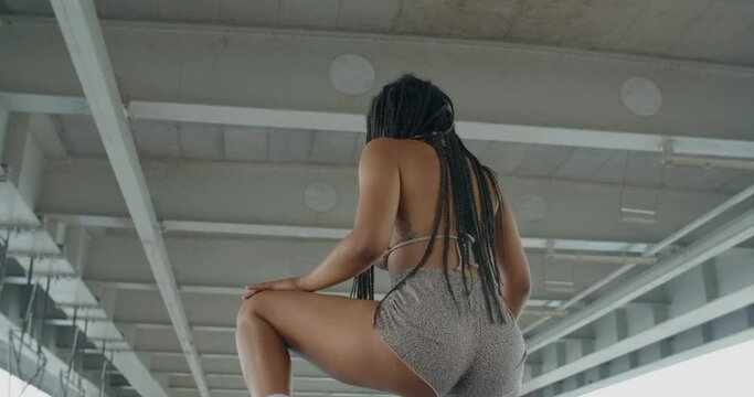 African American woman twerks and dances under a bridge, 4k