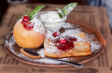 Pancakes with jam and a baked apple on a ceramic plate