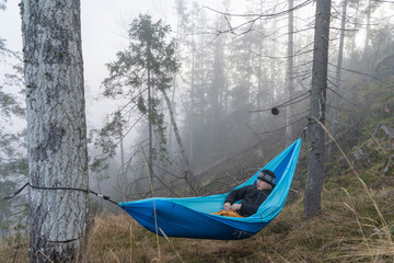 Man relaxing in hammock in the forrest during hiking.
