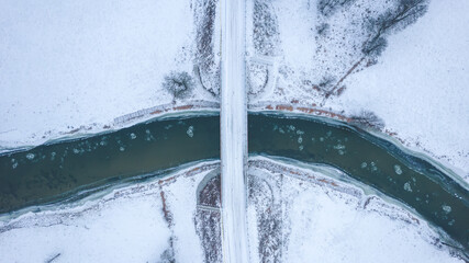 Bridge over the river, winter day. Top down view. Pieces of the ice on the water.