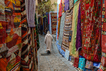 North Africa. Morocco. Chefchaouen. An old man dressed in a djellaba walking in a street of the medina - obrazy, fototapety, plakaty